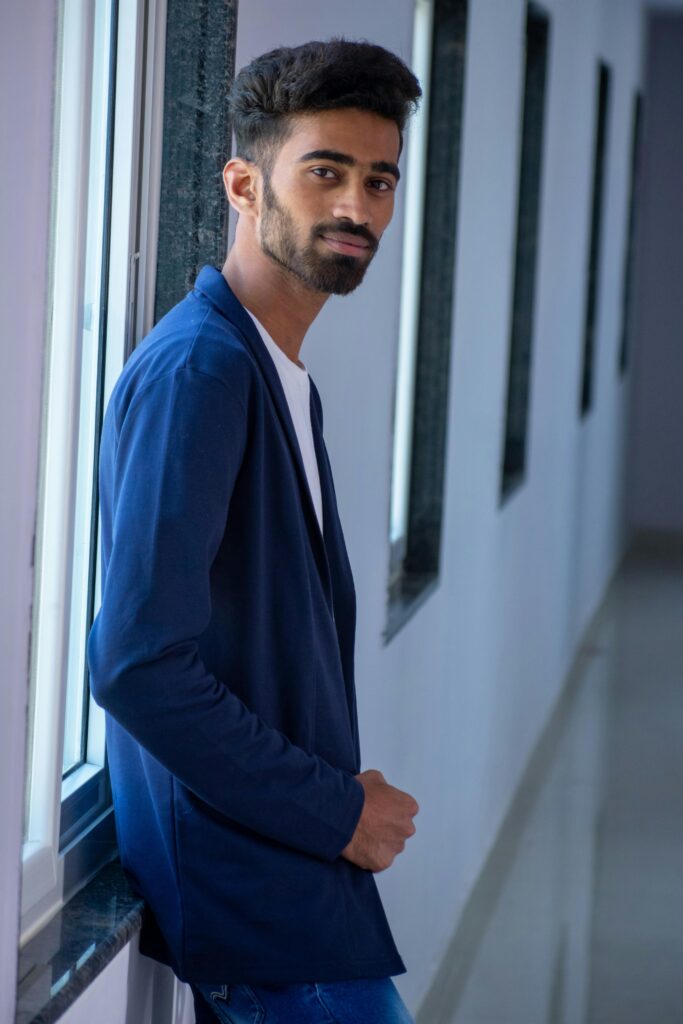 Portrait of a handsome young man in blue formal wear by a window.